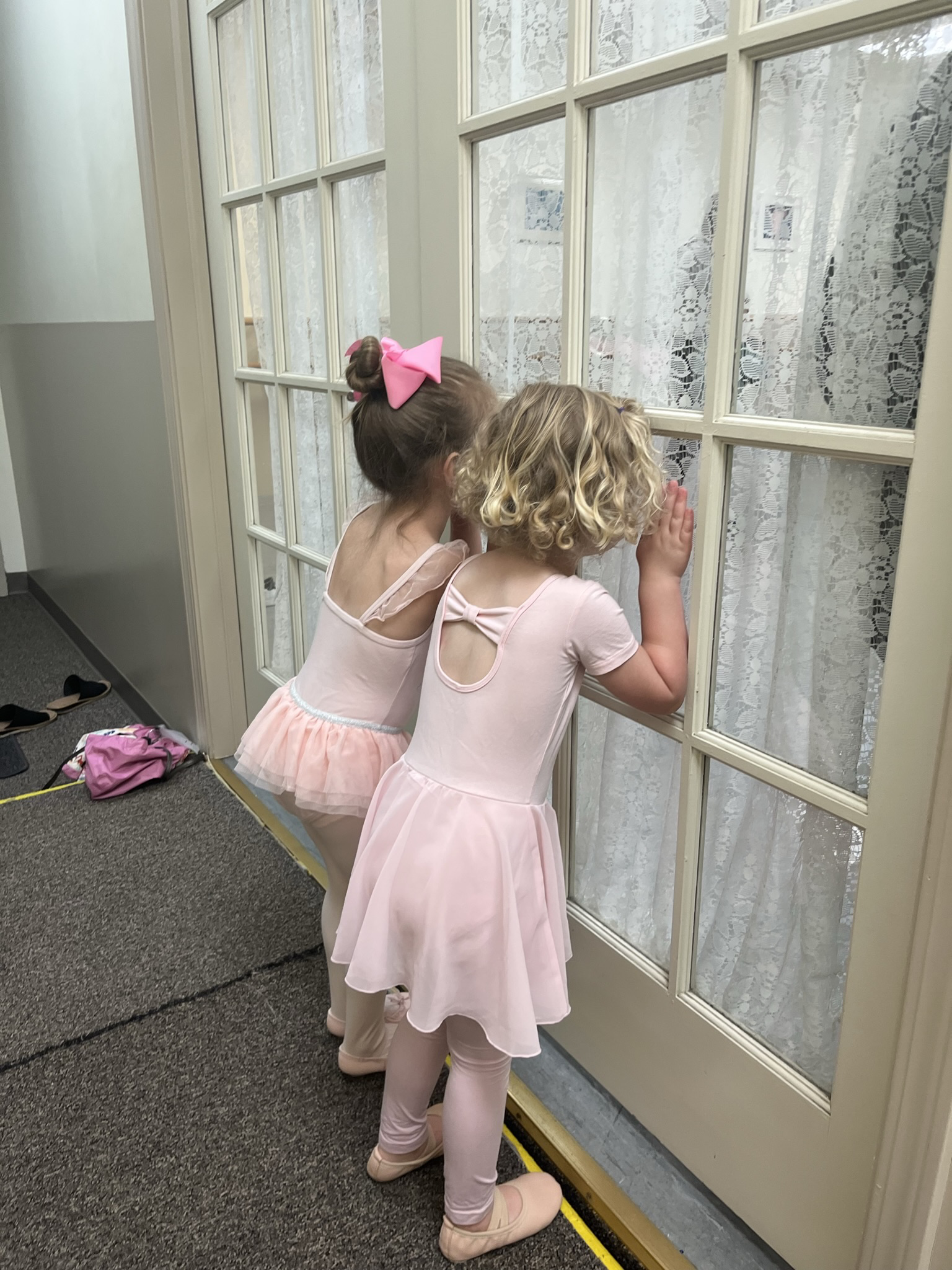 young dancers in pink leotards peeking in window at arlington dance academy